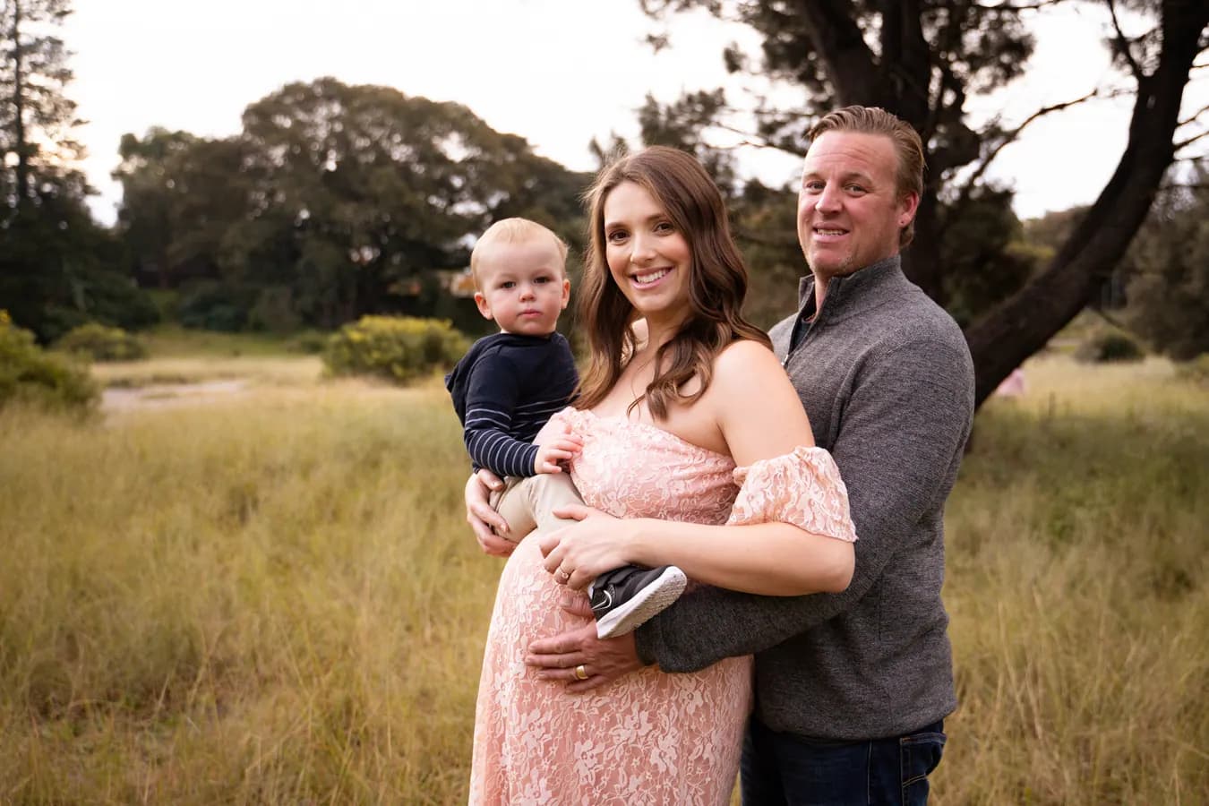 Courtney pregnant with her second baby, outdoors with her husband and their toddler